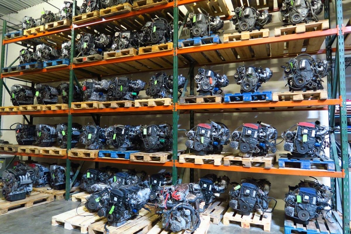 Rows of four-cylinder engines on wooden pallets with green stock tags